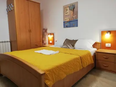 a bedroom with a large bed with a yellow blanket at Apartments Familia in Budva