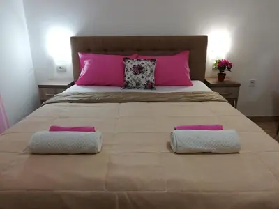a large bed with two pillows and pink pillows at Apartments Familia in Budva