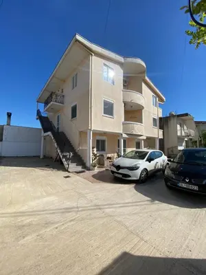 a building with two cars parked in a parking lot at Starlight Apartments in Ulcinj