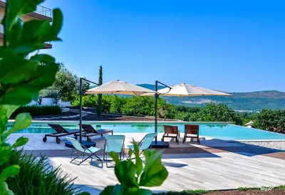 a swimming pool with chairs and umbrellas next to it at A1 2 beds 2 baths Lux Condo Pool Sea Views in Tivat
