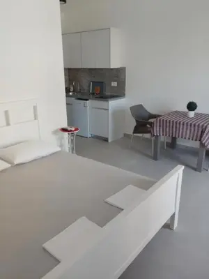 a white living room with a table and a kitchen at Top Apartments in Dobra Voda