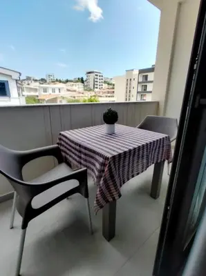 a table and chairs on a balcony with a potted plant at Top Apartments in Dobra Voda