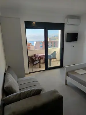 a living room with a couch and a view of a table at Top Apartments in Dobra Voda