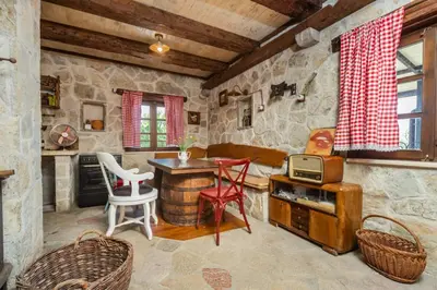 a living room with a table and chairs in a stone room at Guest House Vrelo in Virpazar