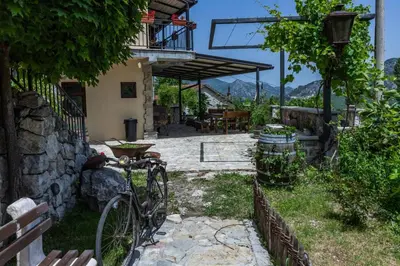 a bike parked outside of a house with a patio at Guest House Vrelo in Virpazar
