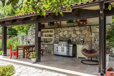 an outdoor kitchen with a stove and a table at Guest House Vrelo in Virpazar