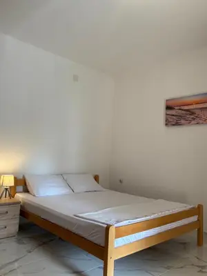 a bed in a room with a white wall at Apartments Sara 2 in Ulcinj
