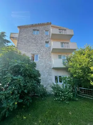 a tall brick building with trees in front of it at Apartments KinGs in Petrovac na Moru
