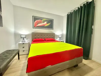 a bedroom with a yellow and red bed and green curtains at Modern One bedroom Apartment Budva in Budva