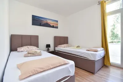 two beds in a room with a window at Apartment near Old Town in Budva