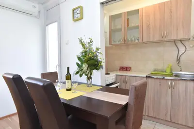 a kitchen with a wooden table with a bottle of wine at Apartment near Old Town in Budva