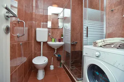 a bathroom with a toilet and a sink and a washing machine at Apartment near Old Town in Budva