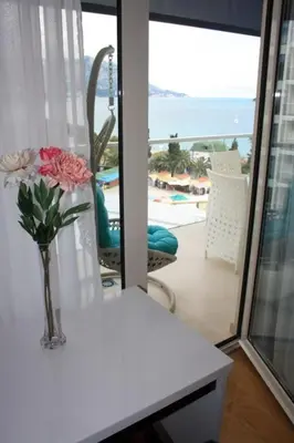 a vase of flowers on a table in a room with a balcony at Luxury Apartment Anastasia Tre canne in Budva