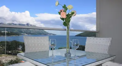 a table with glasses and a vase with flowers on it at Luxury Apartment Anastasia Tre canne in Budva