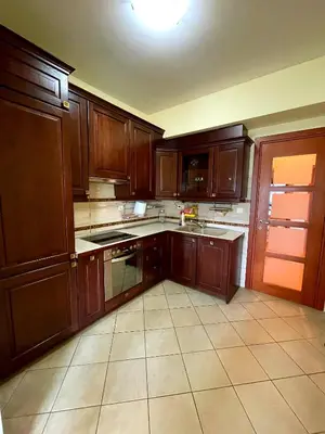 a kitchen with wooden cabinets and a tile floor at Central Rusitc Apartment in Podgorica