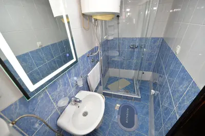 a blue tiled bathroom with a toilet and a sink at the Right Choice Apartment in Kotor