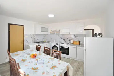 a kitchen with a table and chairs and a kitchen with white cabinets at the Right Choice Apartment in Kotor