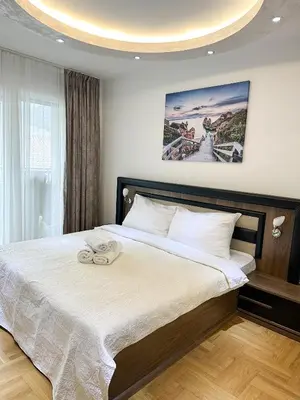 a bedroom with a large bed with a white blanket at AvR Barka Budva in Budva