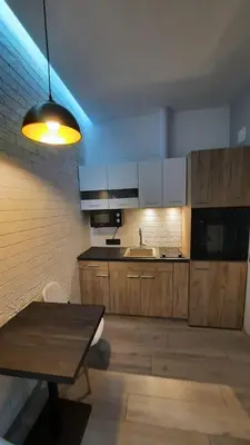 a kitchen with wooden cabinets and a table and a light at Beach Pearl in Sutomore