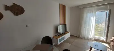 a living room with a television and a table and a window at Biserni Apartman 1 in Kotor
