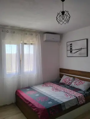 a bedroom with a bed and two windows at Talic Apartmani in Sutomore