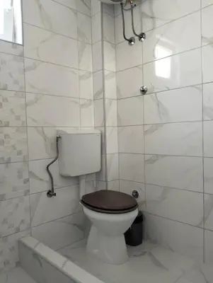 a white bathroom with a toilet with a wooden seat at Talic Apartmani in Sutomore