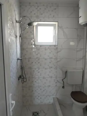 a bathroom with a shower with a toilet and a window at Talic Apartmani in Sutomore