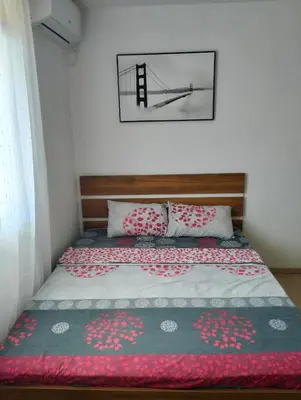 a bedroom with a bed with a blanket and a bridge at Talic Apartmani in Sutomore