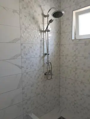 a shower with a shower head in a bathroom at Talic Apartmani in Sutomore