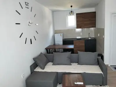 a living room with a couch and a clock on the wall at Talic Apartmani in Sutomore
