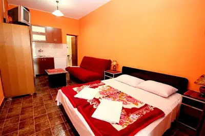 a bedroom with a bed and a red couch at Apartmani Dresic in Sutomore