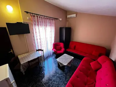 a living room with a red couch and a red chair at Apartmani Dresic in Sutomore