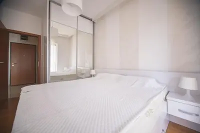 a white bedroom with a white bed and a mirror at Vista Suite in Budva