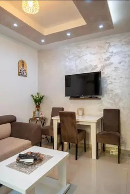 a living room with a table and a tv on a wall at Apartmani Milica Mica Kotor Dobrota in Kotor