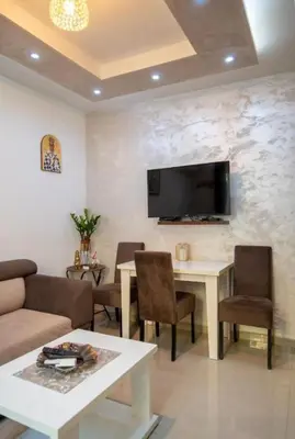 a living room with a table and a tv on a wall at Apartmani Milica Mica Kotor Dobrota in Kotor
