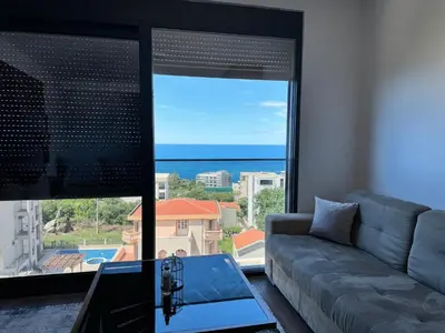 a living room with a couch and a view of the ocean at Apartman Gold.HD in Dobra Voda