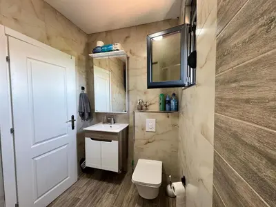 a bathroom with a toilet and a sink and a mirror at Apartman Gold.HD in Dobra Voda