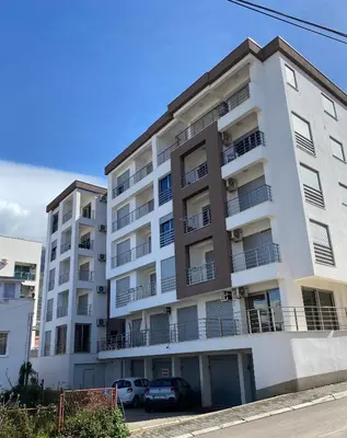 an apartment building with cars parked in front of it at Sunrise Apartments 1 in Dobra Voda