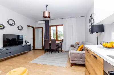 a kitchen and living room with a table and a couch at Apartman DELUXE in Budva