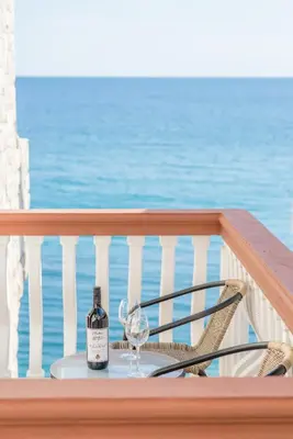 a bottle of wine and a glass on a table on a balcony at Apartmani Stari Grad in Sutomore