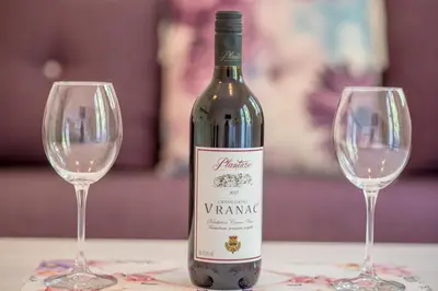 a bottle of wine sitting next to two wine glasses at Apartmani Stari Grad in Sutomore