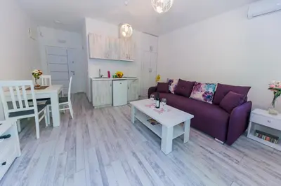 a living room with a purple couch and a table at Apartmani Stari Grad in Sutomore