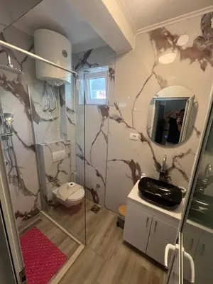 a bathroom with a shower and a sink and a mirror at Apartmani Stari Grad in Sutomore