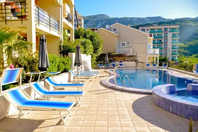 a hotel with a pool and lounge chairs and umbrellas at The Sun & Sea Apartment in Becici