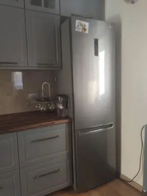 a stainless steel refrigerator in a kitchen with white cabinets at KOTOR OLD TOWN 2 bedroom apartment in Kotor