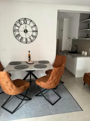 a table and chairs in a kitchen with a clock on the wall at Apartman ANNA ATINA Budva in Budva