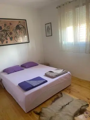 a bedroom with a bed with purple pillows on it at Kadmi in Njeguši