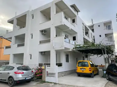 a white building with two cars parked in front of it at Apartments Pericic LUX in Sutomore