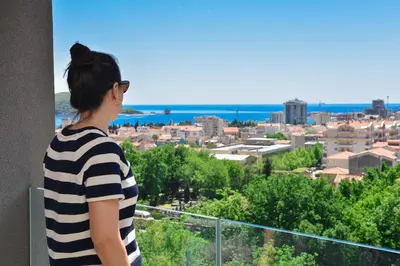 a woman standing on a balcony looking out at a city at New Chill and Go Apartments in Budva