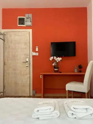 a bedroom with an orange wall with a bed and a tv at Themis Apartment in Kotor